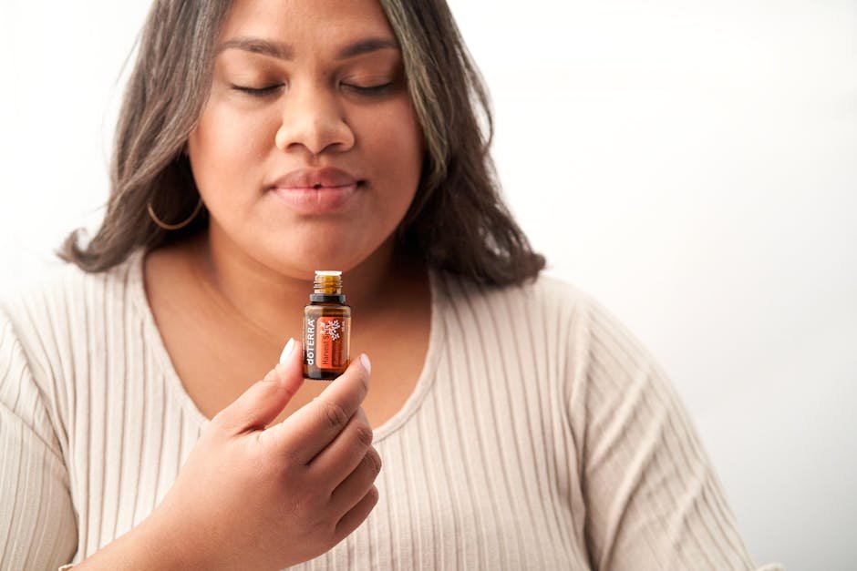 Woman using a personal aromatherapy inhaler during a quiet moment by a window