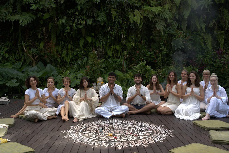 Yoga retreat group meditating outdoors at sunrise on coastal platform with ocean view